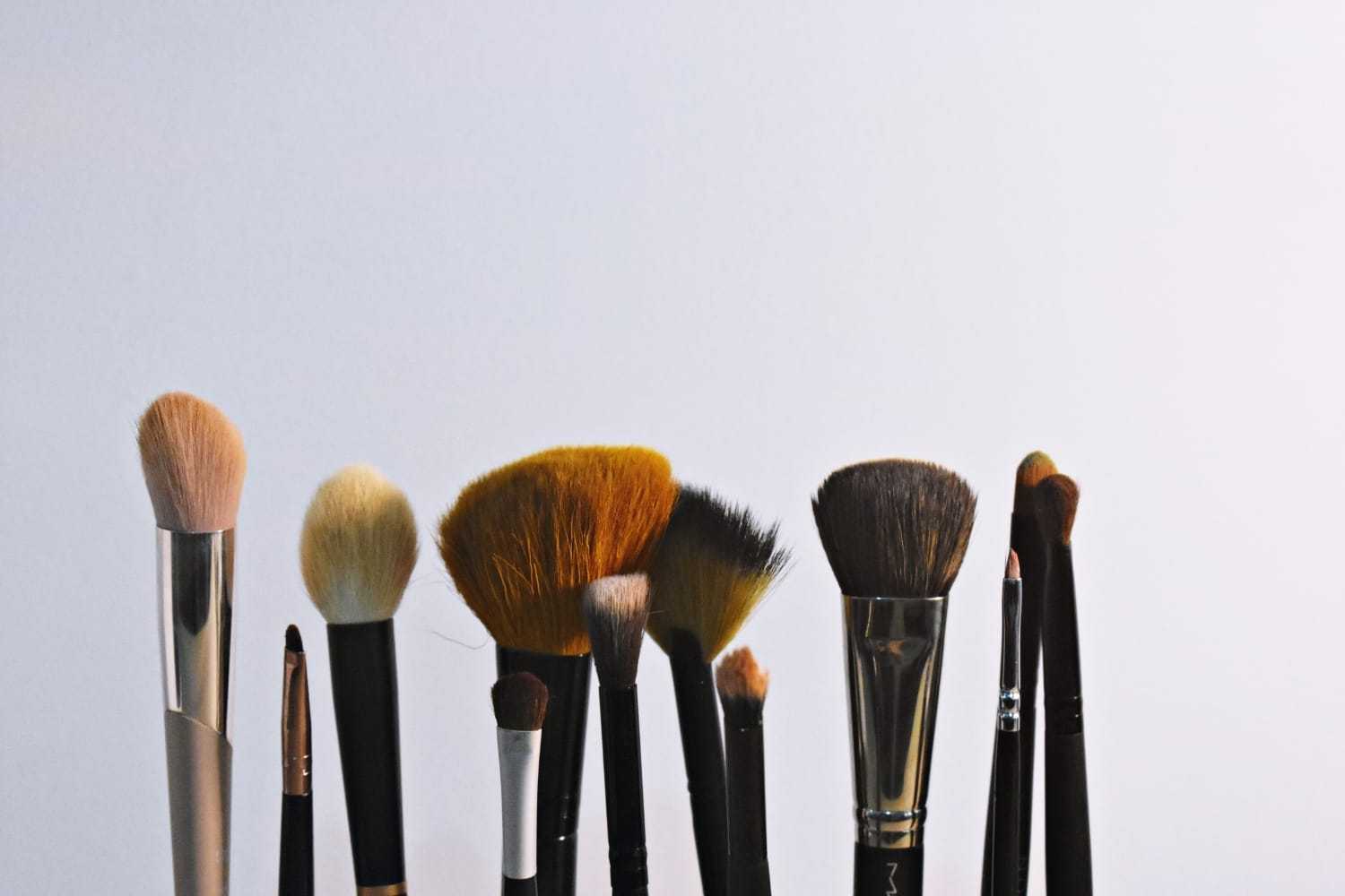 Makeup brushes in various shapes and sizes against a light background.